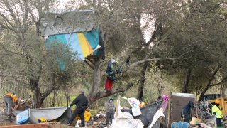 San Jose workers and Tucker Construction employees clear tents and makeshift dwellings along the Coyote Creek Trail in San Jose, Calif. on March 15, 2021. The city’s sweep of encampments ahead of planned renovations of San Jose’s Coyote Creek Trail may result in the largest homeless encampment abatements since the city cleared the infamous Jungle encampments in 2014.