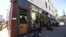 Thirty-year Caffe Trieste worker Paul Maedje takes a coffee order from inside a takeout window.