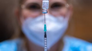 An employee draws up a syringe and a container with the BioNTech/Pfizer vaccine, in Schwaz, Austria.