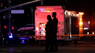 Two police officers stand outside an office building where a shooting occurred in Orange, Calif., March 31, 2021. The shooting killed several people, including a child, and injured another person before police shot the suspect, police said.