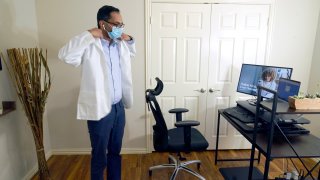 Medical director of Doctor on Demand Dr. Vibin Roy prepares to conduct an online visit with a patient from his work station at home