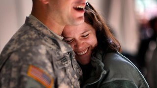 U.S. Army National Guard Sergeant 1st Class Jeremy Commander of the 53rd Infantry Brigade Combat Team is hugged by his wife Korinne