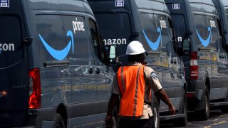 Amazon vans line up at a distribution center to pick up packages for delivery on Amazon Prime Day in Orlando, Florida.