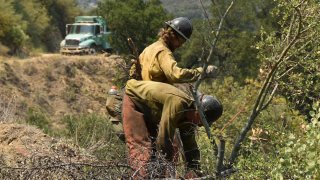 Firefighters work in steep terrain at the Willow Fire near Big Sur, California, June 20, 2021. Dozens of wildfires were burning in hot, dry conditions across the U.S. West. In California, firefighters still faced the difficult task of trying to contain a large forest fire in rugged coastal mountains south of Big Sur that forced the evacuation of a Buddhist monastery and nearby campground.