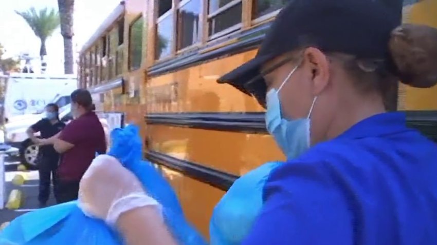 A worker carries free meals off a school bus for delivery to students during the COVID-19 pandemic.