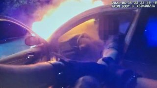 An officer pulls a driver out of a burning vehicle.