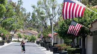 A man walks along a street where U.S. flags fly.