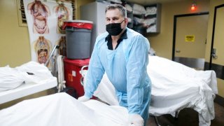 LONG BEACH, CALIFORNIA – MARCH 16: (EDITOR’S NOTE: Editorial use only.) Owner Ken McKenzie stands for a photograph in his mortuary among an overflow of the deceased amid the COVID-19 pandemic at McKenzie Mortuary Services on March 16, 2021 in Long Beach, California. McKenzie opened his mortuary during the AIDS epidemic, while some of his friends were dying of the disease. He openly received the bodies of AIDS victims without charging extra fees or turning away families. The mortuary was overwhelmed with cases in 2021 following a COVID-19 surge in Southern California. As of April 14, the mortuary had received 465 death cases this year, most of which were COVID-19 related. Over the same time period in 2020, they had received 213 total cases. (Photo by Mario Tama/Getty Images)