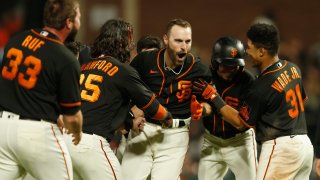 Curt Casali #2 of the San Francisco Giants celebrates with teammates after hitting a walk-off RBI double in the bottom of the tenth inning against the Oakland Athletics at Oracle Park on June 26, 2021 in San Francisco, California.
