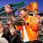 A Giants fan dressed in orange stands up and cheers