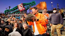 A Giants fan dressed in orange stands up and cheers