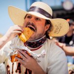a man in a Giants jersey eats a huge taco