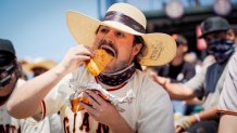 a man in a Giants jersey eats a huge taco