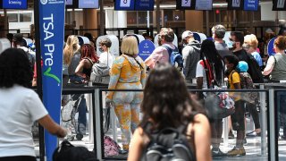 Travelers wait in line at a Transportation Security Administration (TSA) screening checkpoint at Orlando International Airport in May, 2021.