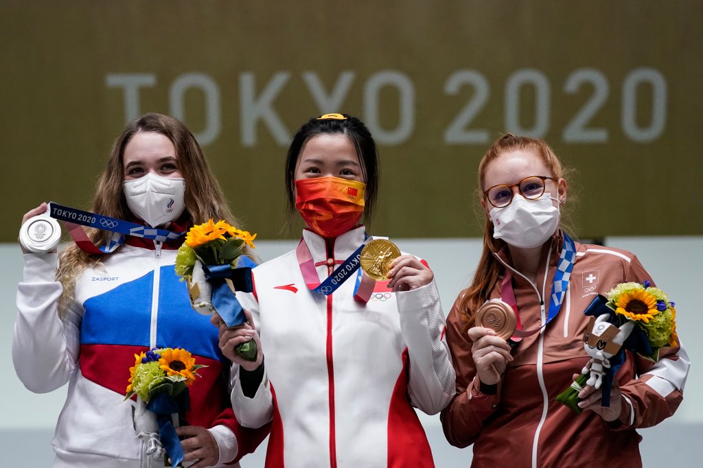 Silver medalist Anastasiia Galashina, left, of the Russian Olympic Committee, gold medalist Yang Qian, of China, center, and bronze medalist Nina Christen, of Switzerland stand after the women's 10-meter air rifle at the Asaka Shooting Range in the 2020 Summer Olympics, Saturday, July 24, 2021, in Tokyo, Japan.