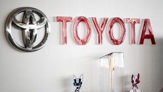 This picture shows a Toyota logo next to the Tokyo 2020 Olympic and Paralympic Games mascots and torch at a closed Toyota showroom in Tokyo on May 12, 2021.