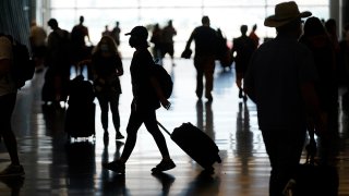 FILE - In this July 1, 2021, file photo, people travel through Salt Lake City International Airport in Salt Lake City.
