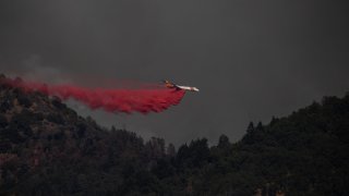 A plane releases fire retardant on a ridge while battling the Salt Fire.