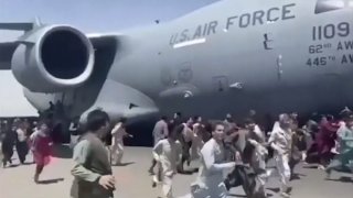 Some hundreds of people run alongside a U.S. Air Force C-17 transport plane as it moves down a runway of the international airport, in Kabul, Afghanistan, Monday, Aug. 16. 2021.