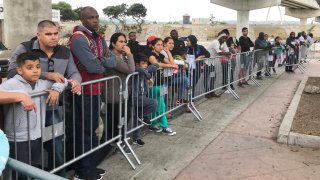 FILE - In this Sept. 26, 2019, file photo asylum seekers in Tijuana, Mexico, listen to names being called from a waiting list to claim asylum at a border crossing in San Diego. The Supreme Court has ordered the reinstatement of the "Remain in Mexico" policy, saying that the Biden administration likely violated federal law by trying to end the Trump-era program that forces people to wait in Mexico while seeking asylum in the U.S. The decision immediately raised questions about what comes next for the future of the policy, also known as the Migrant Protection Protocols.