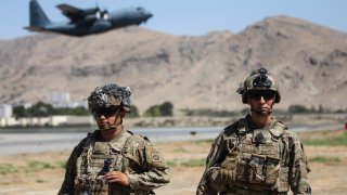 In this image provided by the Department of Defense, two paratroopers assigned to the 1st Brigade Combat Team, 82nd Airborne Division conduct security while a C-130 Hercules takes off during a evacuation operation in Kabul, Afghanistan