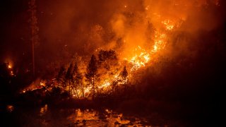 The Caldor Fire burns above the South Fork of the American River in the White Hall community of El Dorado County, Calif., on Friday, Aug. 27, 2021.