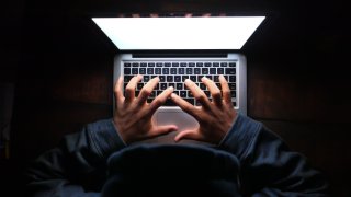 Hooded Hacker Stealing Data From Laptop At Night