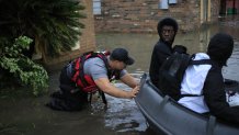 A first responder pushes a rescue boat with residents aboard through floodwaters left behind by Hurricane Ida in LaPlace, Louisiana, U.S., on Monday, Aug. 30, 2021.
