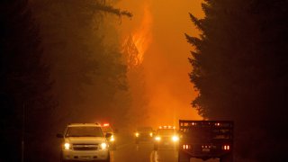 Firefighters monitor the scene as flames from the Dixie fire jump across highway 89 near Greenville, California on August 3, 2021.