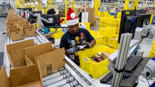Amazon employees load boxes with orders at the company’s fulfillment center ahead of Cyber Monday in Tracy, Calif.