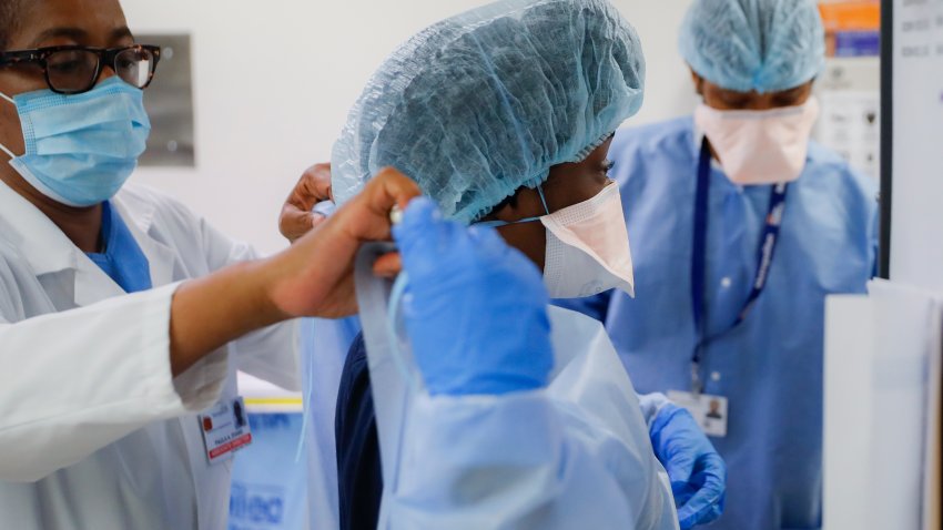 FILE – In this Wednesday, May 27, 2020 file photo, Medical personnel adjust their personal protective equipment while working in the emergency department at NYC Health + Hospitals Metropolitan in New York. Hospitals and nursing homes in New York are bracing for the possibility that a statewide COVID-19 vaccine mandate for health care workers could lead to staff shortages when it takes effect Monday, Sept. 27, 2021. Doctors and nurses — and also support staff, like food service workers and cleaners — have been given until Sept. 27 to get at least their first vaccine shot in one of the nation’s most aggressive plans to protect patients.
