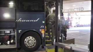 FILE - In this Thursday, Feb. 13, 2020 file photo, agents for Customs and Border Protection board a Greyhound bus headed for Portland, Ore., at the Spokane Intermodal Center, a terminal for buses and Amtrak, in Spokane, Wash. Greyhound Lines Inc. will pay $2.2 million to settle a lawsuit over the bus line's practice of allowing U.S. Customs & Border Protection agents to board its buses in Washington state to conduct warrantless immigration sweeps, the state attorney general said Monday, Sept. 27, 2021.