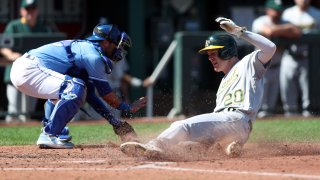 Mark Canha #20 of the Oakland Athletics slides safely into home plate.