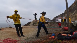 Crews work at the scene of a deadly crash off Highway 1 near Pacifica.