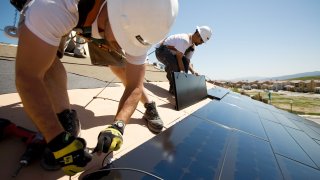 Construction workers install SunPower tiles on homes in San Ramon, Calif.