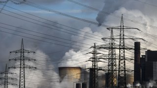 Electricity pylons are seen in front of the cooling towers of the coal-fired power station of German energy giant RWE in Weisweiler, western Germany, on January 26, 2021.