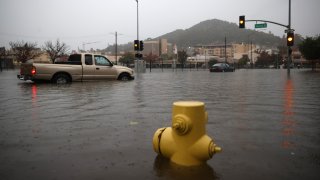 Cars try to navigate a flooded street in San Rafael.