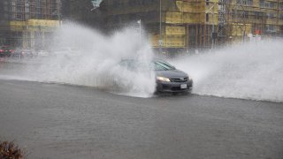 A vehicle drives through a waterlogged road.