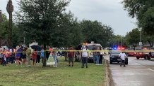 Students and families stand outside a staging area after a shooting inside the YES Prep Southwest Secondary in southwest Houston, Oct. 1, 2021.