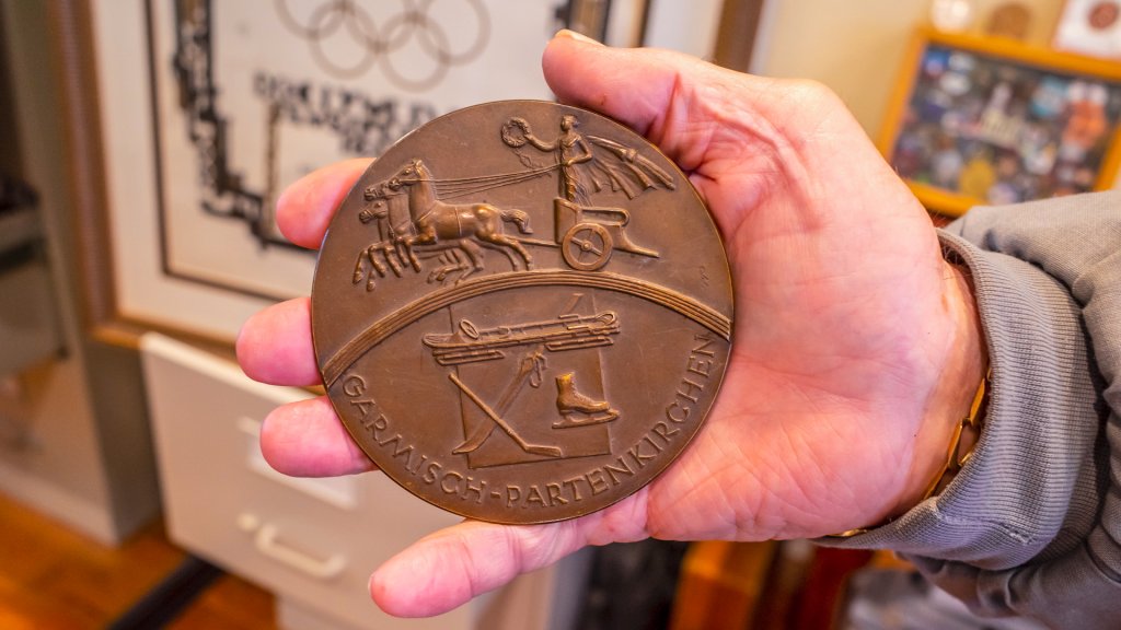 a hand holds a giant bronze medal