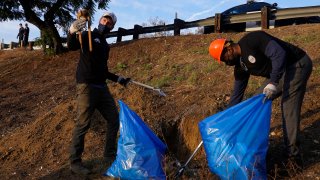California Gov. Gavin Newsom, left, and Caltrans director Adetokunbo "Toks"Omishakin, right, pick up trash along the CA-110 freeway in Los Angeles Wednesday, Dec. 15, 2021.