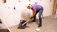 a woman smashes a laptop computer with a baseball bat