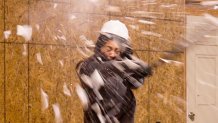 a woman smashes a plate with a baseball bat, fragments flying everywhere