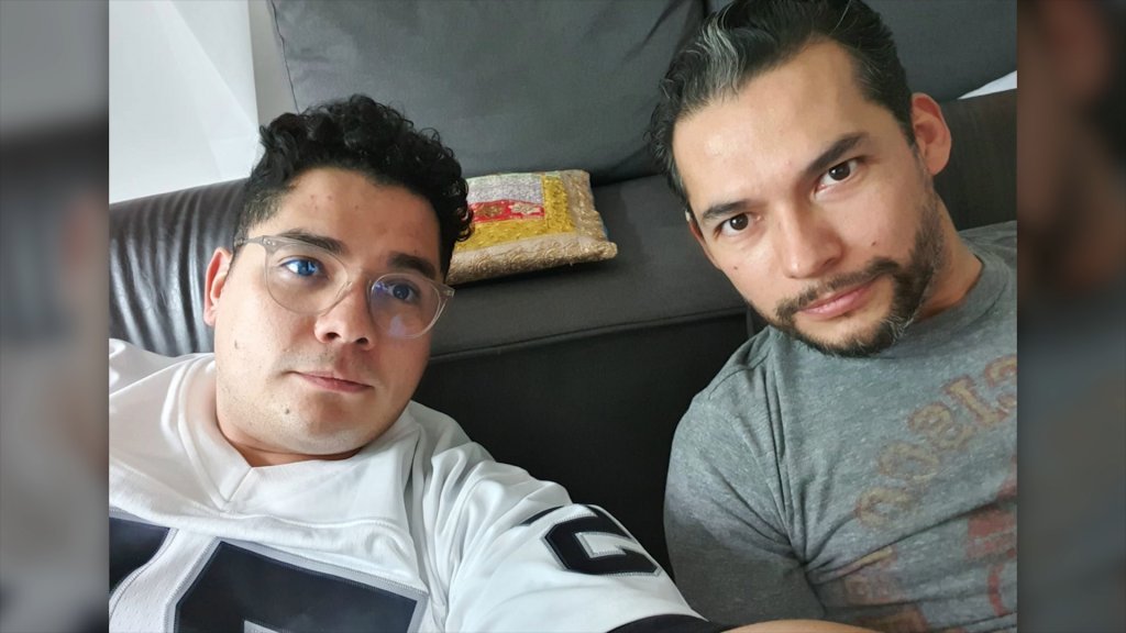 Two men posing for selfie.  One of them is wearing a black and white soccer jersey.