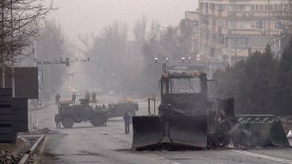 TOPSHOT - Servicemen and their military vehicles block a street in central Almaty on January 7, 2022, after violence that erupted following protests over hikes in fuel prices. - Kazakhstan's president on January 7 rejected calls for talks with protesters after days of unprecedented unrest, vowing to destroy "armed bandits" and authorising his forces to shoot to kill without warning. He said earlier that order had mostly been restored across the country, after protests this week over fuel prices escalated into widespread violence, especially in main city Almaty.