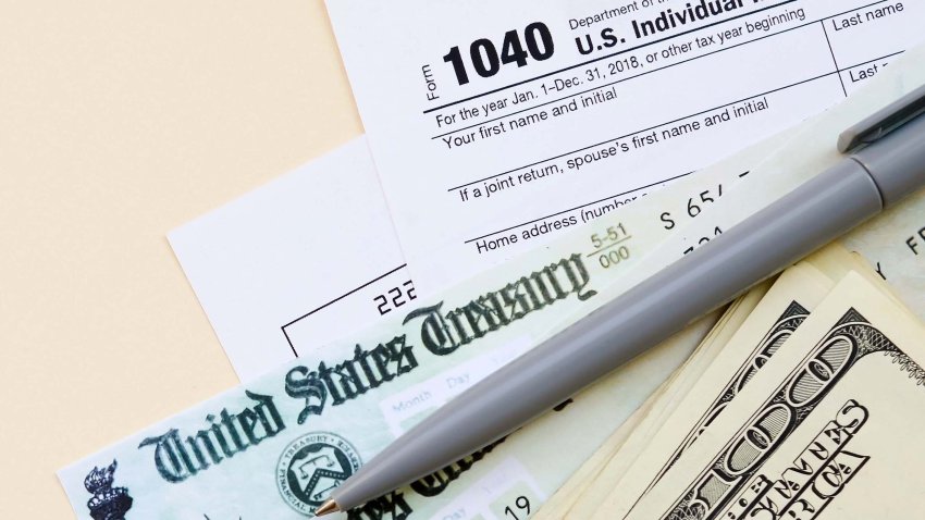 1040 Individual Income tax return form with Refund Check and hundred dollar bills on beige background