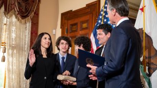 Patricia Guerrero, left, is sworn-in to the California Supreme Court on Monday, March 28, 2022, by Gov. Gavin Newsom at the Stanford Mansion in Sacramento. She is joined by her sons Anthony, 15, left, and Christopher, 14, holding a family Bible, and her husband, Joe Dyson.