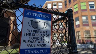 A sign encouraging mask use hangs on a fence before the local school council and the Chicago Teachers Union held a press conference Tuesday, Sept. 28, 2021 outside Jensen Elementary School in Chicago's North Lawndale neighborhood. (Brian Cassella/Chicago Tribune/Tribune News Service via Getty Images)