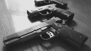 A close-up of three handguns on a table.