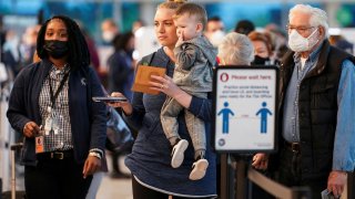 Masked and unmasked travelers line up at a security checkpoint after the Biden administration announced it would no longer enforce a U.S. coronavirus disease (COVID-19) mask mandate on public transportation, following a federal judge’s ruling that the 14-month-old directive was unlawful, at Ronald Reagan Washington National Airport in Arlington, Virginia, U.S., April 19, 2022.